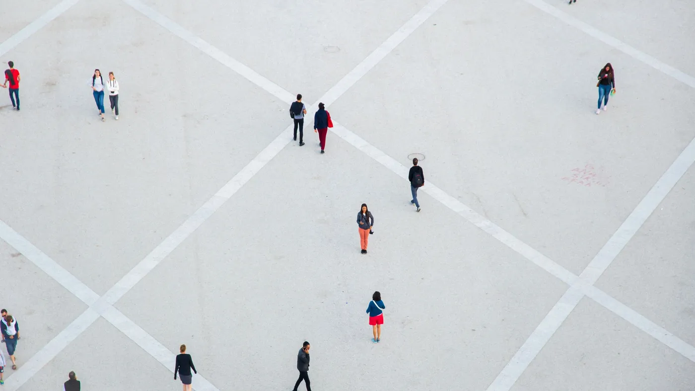 High angle view of people walking across a wide open concrete city square