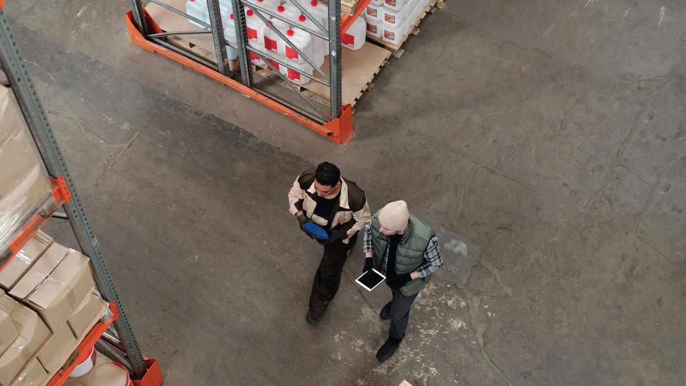 Two warehouse workers checking stock levels together on a digital tablet