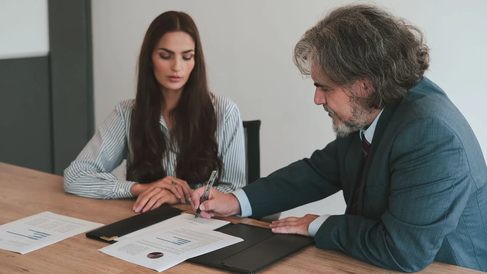 Two colleagues at an office desk reviewing a printed document together