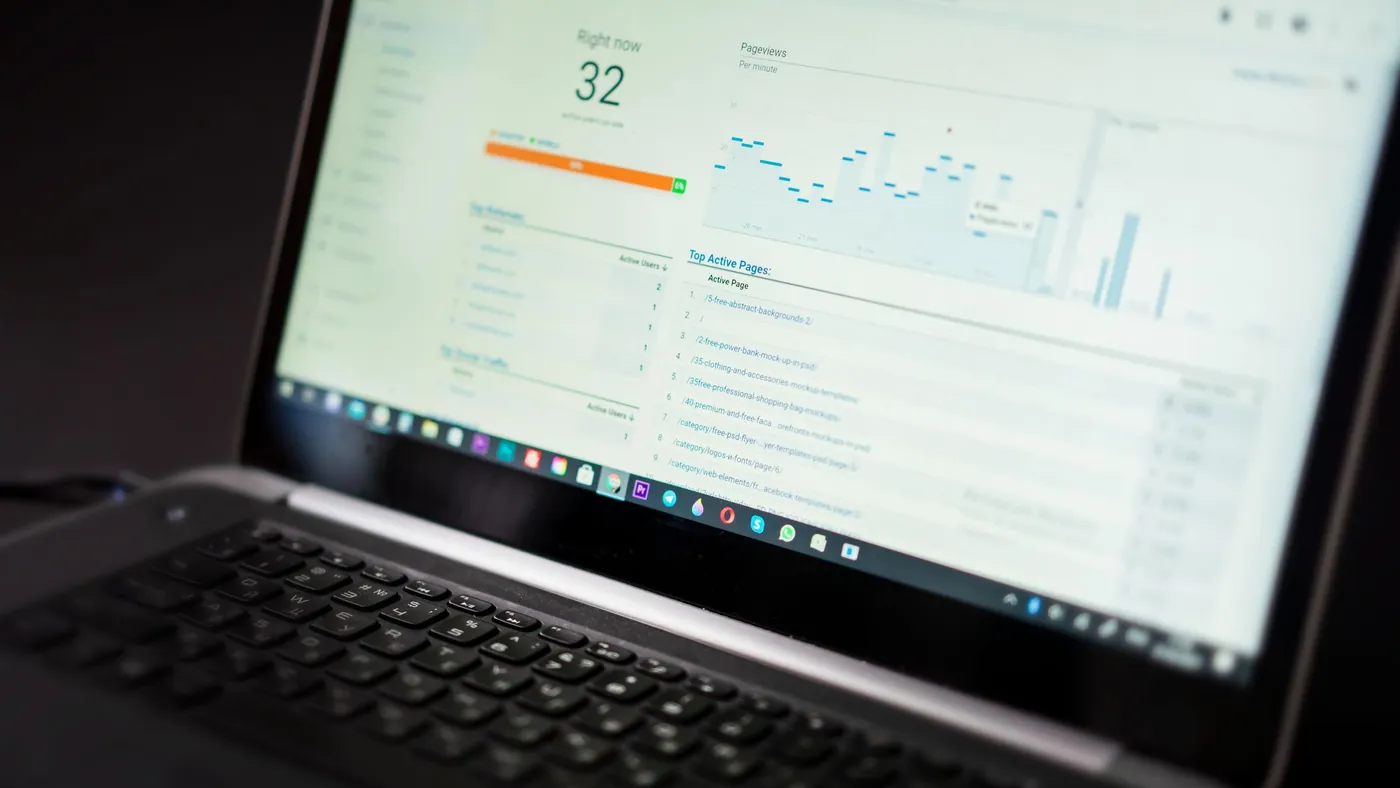 A laptop on a desk displaying an analytics dashboard with charts and tracking data