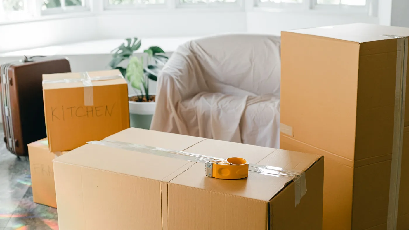Cardboard moving boxes and a suitcase on the floor of an empty apartment