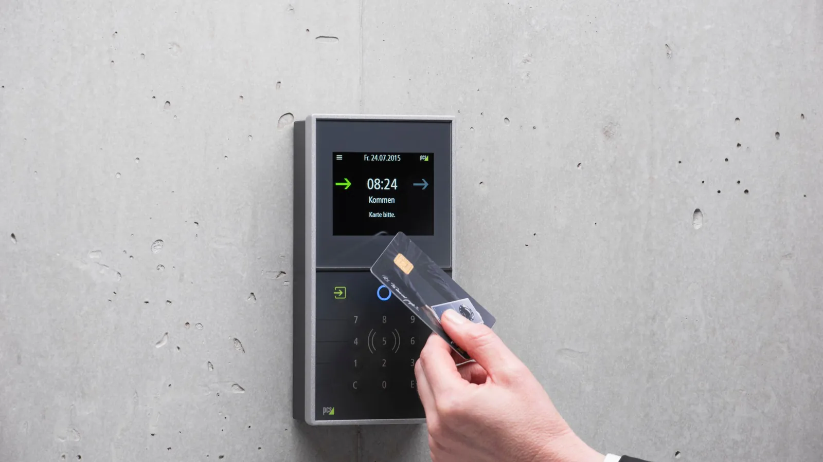 A hand in a suit sleeve holding a key card against a wall-mounted access reader