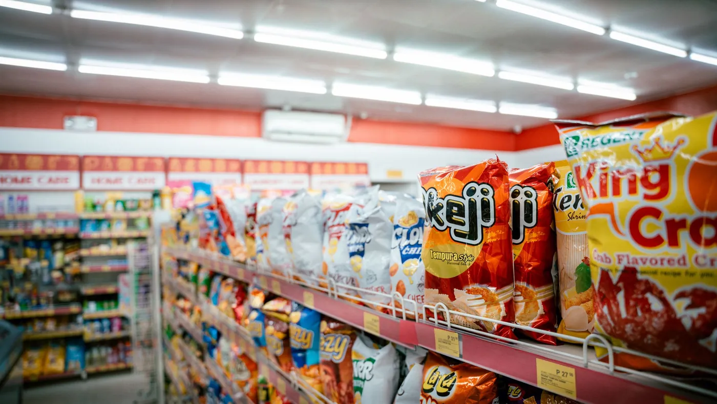 A supermarket snack aisle with rows of chip bags in identical packaging filling every shelf