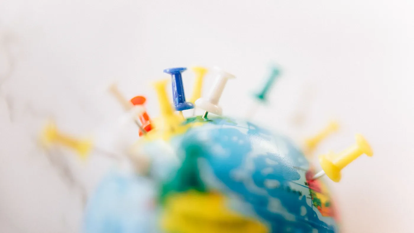 A small desk globe with coloured push pins stuck into several countries