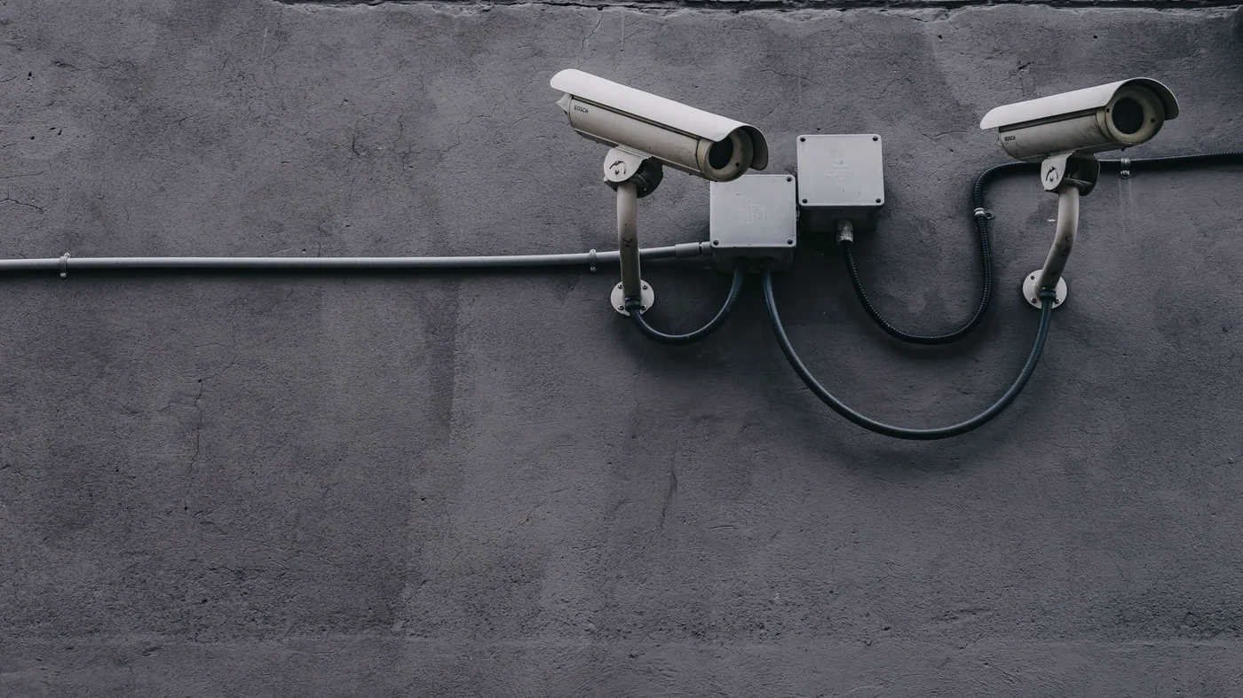 Two grey bullet security cameras mounted on a concrete wall