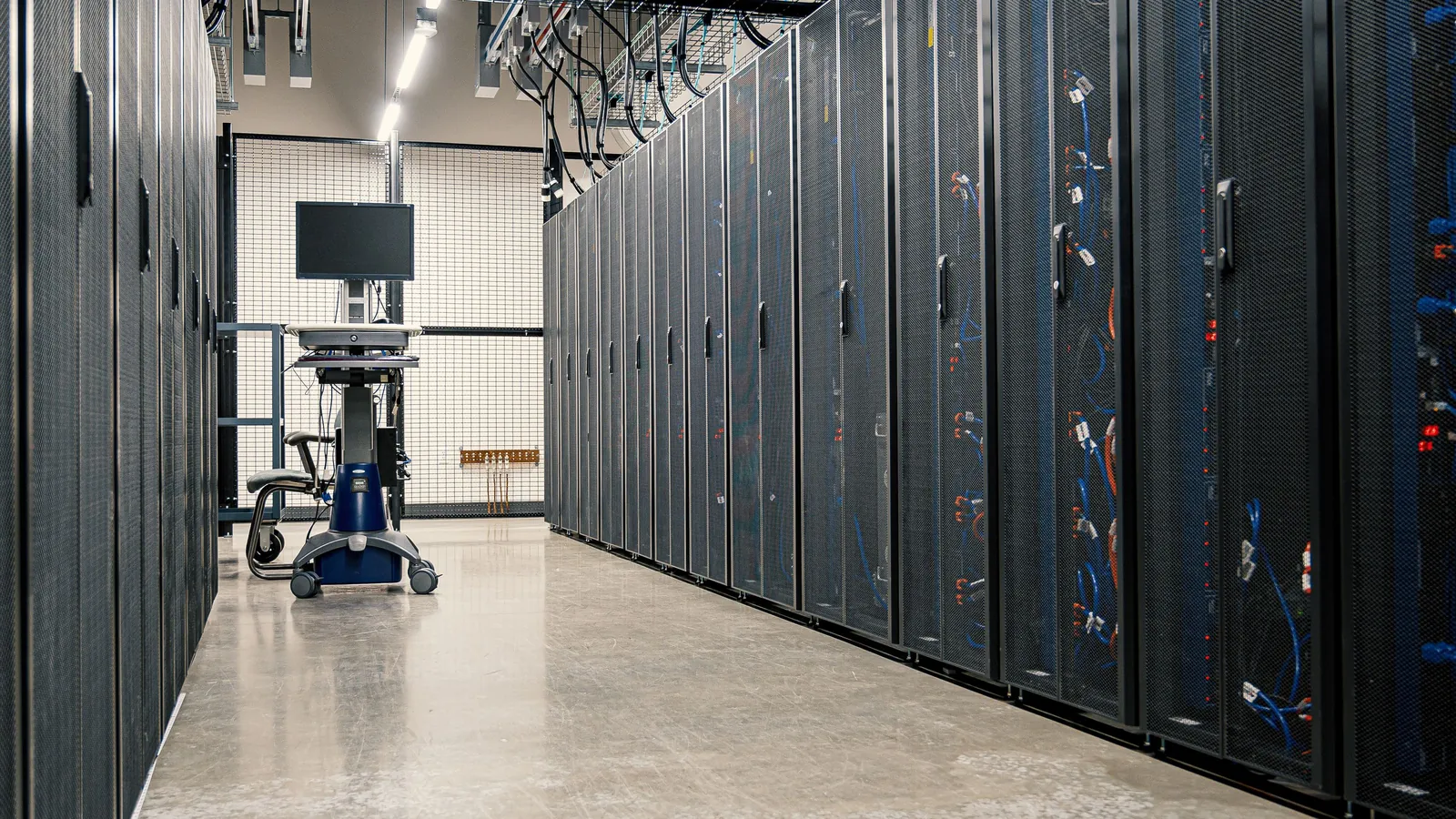 Steel cabinets of servers, networking gear and cabling in a data centre aisle