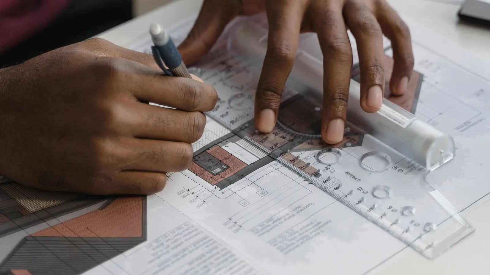 A person drawing a detailed blueprint by hand with a ruler and pencil