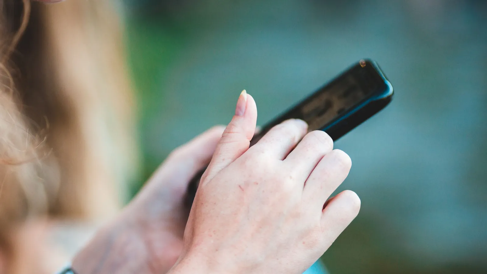 Close-up of a person's hands holding a smartphone against a soft blurred background
