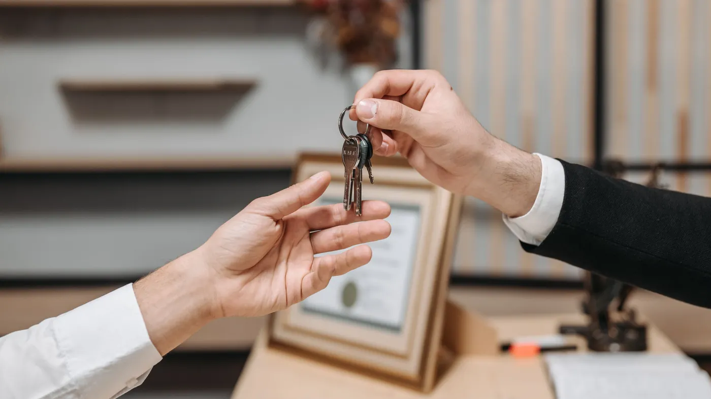 Close-up of one person handing a set of keys to another across a desk